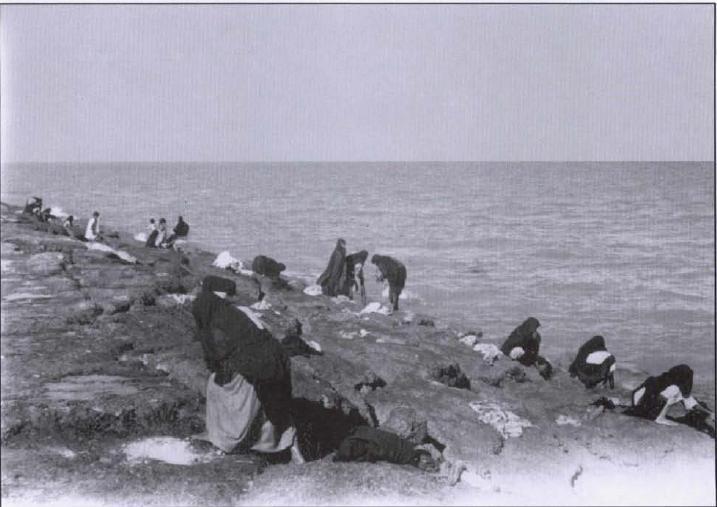 صوره لمجموعة من النساء تقوم بغسل الملابس بمياه البحر