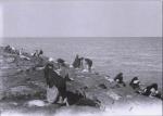 صوره لمجموعة من النساء تقوم بغسل الملابس بمياه البحر